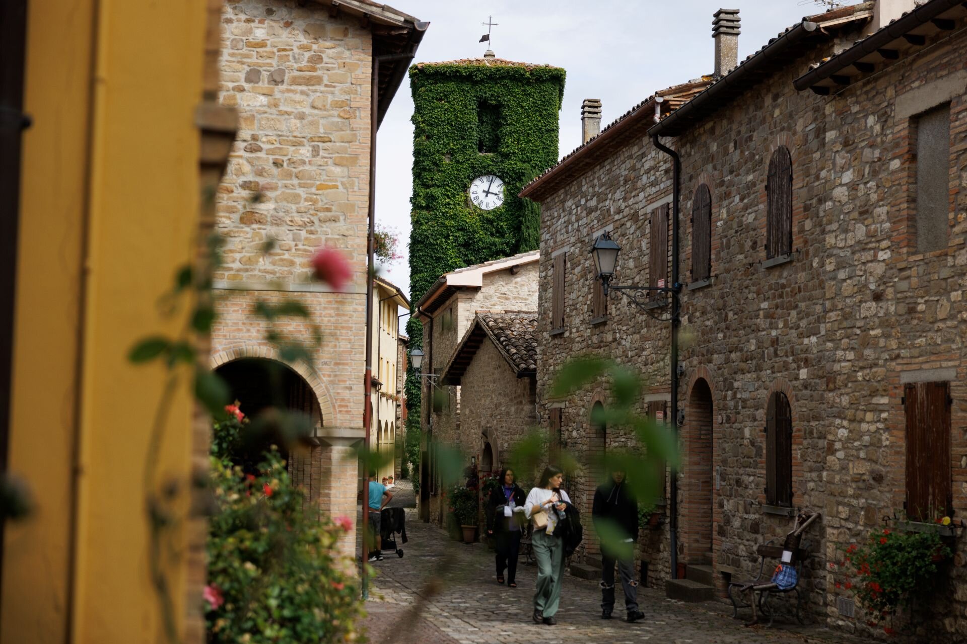 Persone camminano sul una strada a Frontino con case in pietra | © Gianluca Maroccini